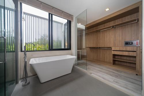 a bathroom with a bath tub and a window at Luxury 5BR Pool Villa near Beach and Golf - Laguna Park 2 in Ban Phru Champa