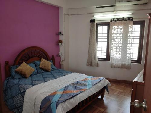 een slaapkamer met een bed met paarse muren en ramen bij Amee's Luxury above the City in Kollam