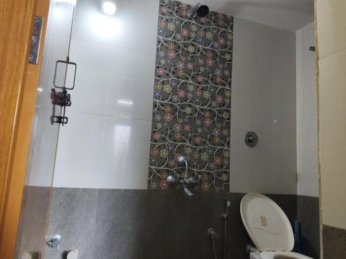 a bathroom with a shower with a toilet and a wall at The Homely Stay - Chandransh Homestay in Udupi