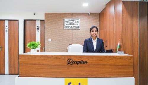 a woman is sitting at a reception desk at FabHotel Vishala In in Ahmedabad