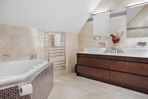 a bathroom with two sinks and a tub and a mirror at Luxury Mansion 7bdrm 6bth pool pizza ovn 25mns CBD in Silverdale
