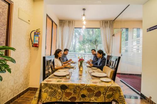 班加罗尔FabHotel Corporate Crown - Nr Jyoti Nivas University的一群人坐在餐厅的一张桌子旁