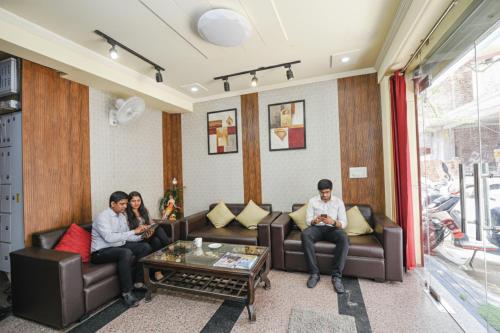 three people sitting on couches in a room at FabHotel Ishtara Auberge - Nr Yashobhoomi Convention Centre in New Delhi