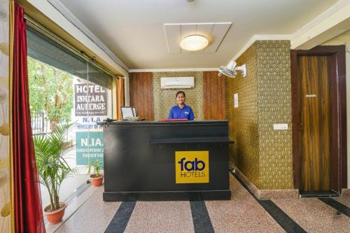 a woman standing at a reception desk in a hotel lobby at FabHotel Ishtara Auberge - Nr Yashobhoomi Convention Centre in New Delhi