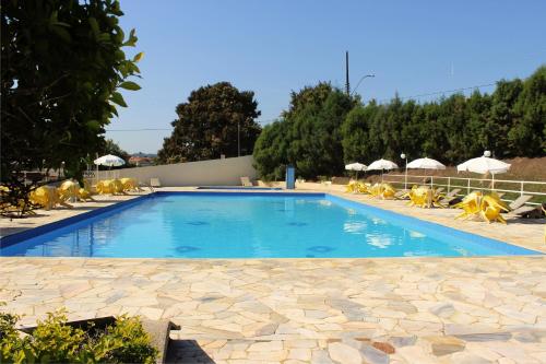a large swimming pool with yellow chairs and umbrellas at Avenida Charme Hotel in Águas de São Pedro