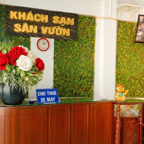 a counter with a vase of red and white flowers at Sân Vườn Hotel Khánh Hòa in Ninh Hòa