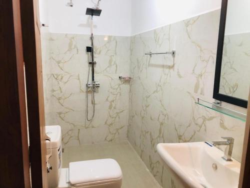 a bathroom with a shower and a toilet and a sink at Sinharaja Cottage in Nelluwa