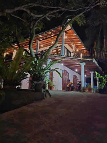 a person sitting on a bench in front of a house at night at Forina Villa in Walliwala East