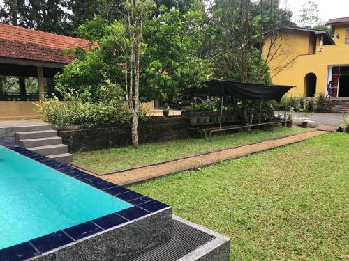 a backyard with a swimming pool and a black umbrella at Sinharaja Cottage in Nelluwa