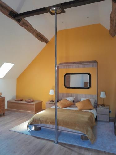 a bedroom with a bed and a yellow wall at Maison de style La Grange in Asquins