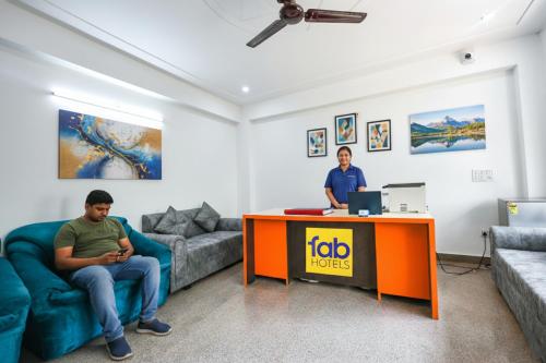 Dos hombres sentados en una sala de estar con una mesa y un escritorio. en FabHotel The Yashobhumi Near Yashobhoomi Convention Centre, en Nueva Delhi