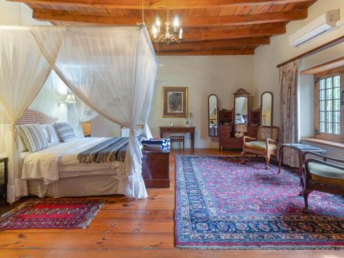 タルバにあるTulbagh Country Guest House - Cape Dutch Quartersのベッドルーム1室(天蓋付きベッド1台、ラグ付)
