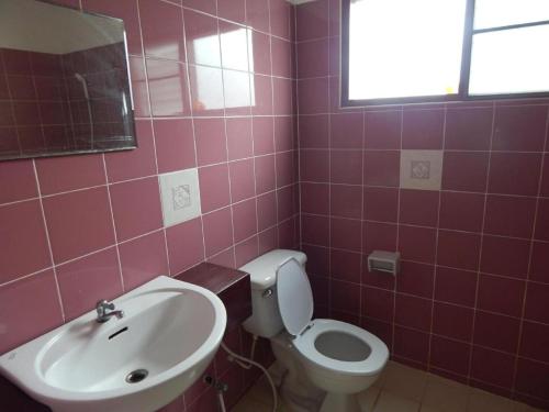 a pink bathroom with a toilet and a sink at Jinta Hotel Nathon Beach in Nathon