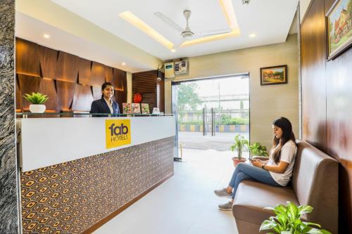 ナビムンバイにあるFabHotel Landmark Residency - Nr MIDC Turbheのロビーのフロントデスクに座って2名