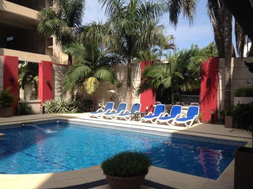 una piscina con sillas azules y palmeras en Condado Hotel Casino Goya en Goya