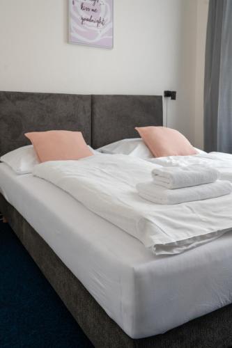 a large bed with white sheets and pink pillows at Hotel CB Royal in České Budějovice
