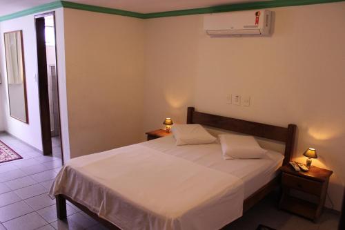 a bedroom with a bed with white sheets and two lamps at Hotel Pousada da Praça in Recife
