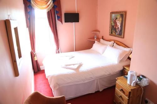 a bedroom with a white bed and a window at Twin Lions Hotel in Edinburgh