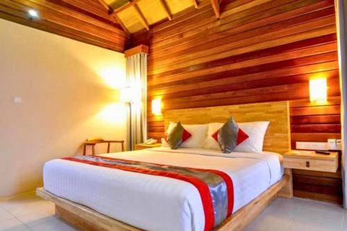 a bedroom with a large bed with wooden walls at Nerissa 2 BR Dazzling Side By Side ZN332 in Gili Air
