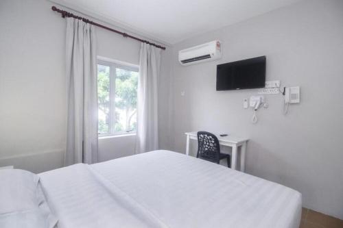 a bedroom with a bed and a desk and a window at OYO 90577 Safi Homestay in Kampong Tanjong Gelam