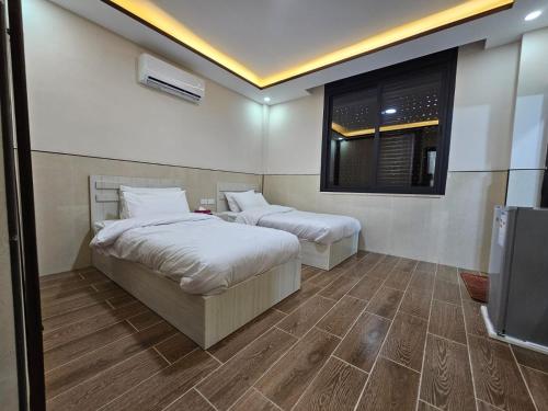 a bedroom with two beds and a television in it at النزل الفندقي مدينة الأمير هاشم بن عبدالله الثاني للشباب in Dulaylat al Ḩamāʼidah