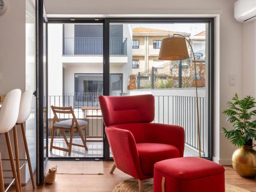 a living room with a red chair and a balcony at Gaia Bella Guest House in Vila Nova de Gaia