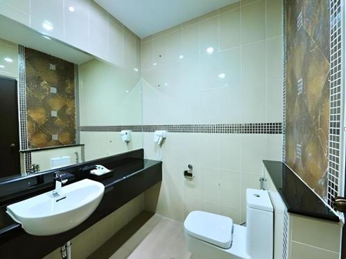une salle de bain avec un lavabo, des toilettes et un miroir dans l'établissement Green World Palace Hotel, à Songkhla