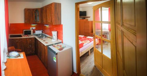 a small kitchen with a refrigerator and a bedroom at AQUA Thermal Sóterápia és Apartmanház in Püspökladány