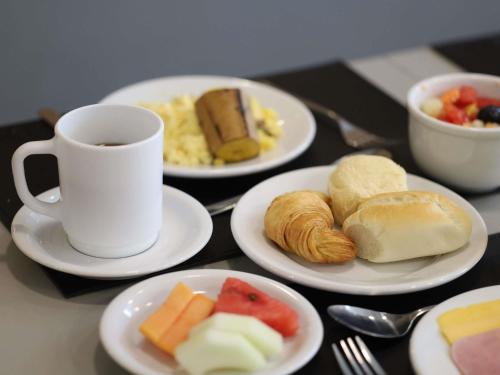 a table with plates of food and a cup of coffee at Ibis Salvador Rio Vermelho in Salvador