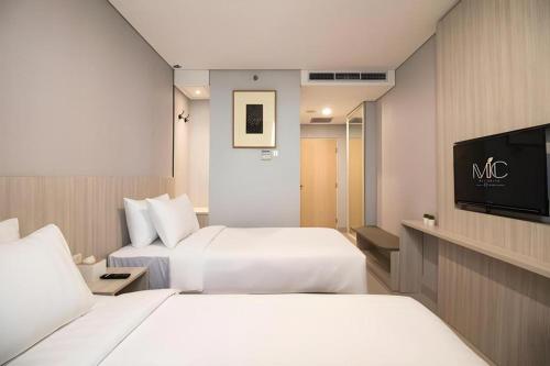 une chambre d'hôtel avec deux lits et une télévision à écran plat dans l'établissement MIC Residence, à Yogyakarta