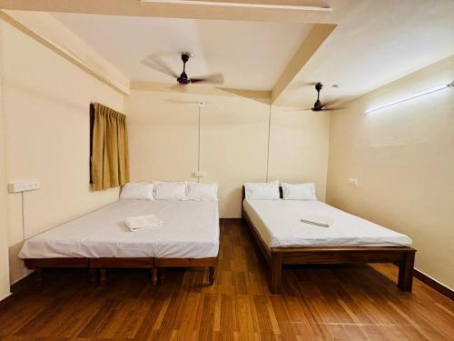 two beds in a room with wooden floors at Citynest Residency in Pondicherry