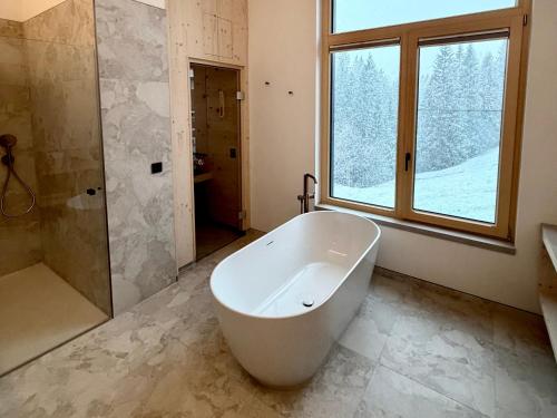 a bathroom with a tub and a shower and a window at Hugo und Pepi Appartements in Mittelberg
