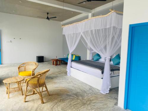 a bedroom with a bed and a table and chairs at Kaori Cafe and Villa in Weligama