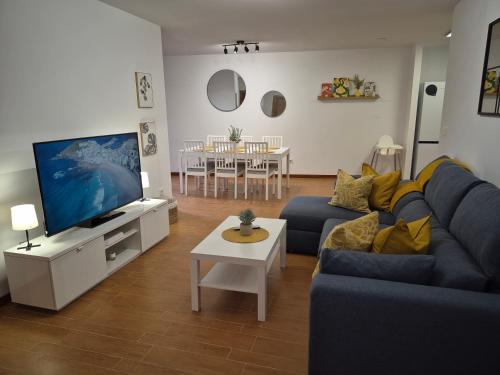 a living room with a blue couch and a tv at Apartamento la Última Orilla - Mar y Garaje in Malpica
