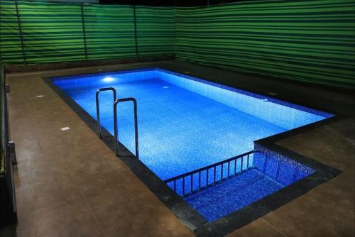 WayanadにあるJosebas Inn Vythiriの- ブルーライト付きの大型スイミングプール