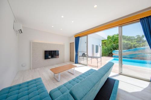 a living room with a blue couch and a pool at シャングリラ沖縄 in Motobu