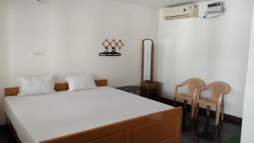 a bedroom with a bed and two chairs at Rainbow Guest House in Mahabalipuram