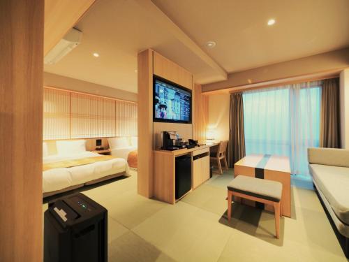 a hotel room with a bed and a television at Henn na Hotel Premier Kyoto Gojo Karasuma -Formerly Watermark Hotel Kyoto- in Kyoto