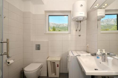 a white bathroom with a toilet and a sink at D&N Apartment in Kaštela