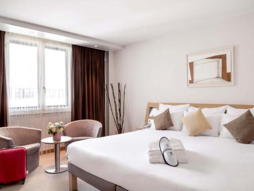 a bedroom with a large white bed and a red suitcase at Novotel Paris Roissy CDG Convention in Roissy-en-France