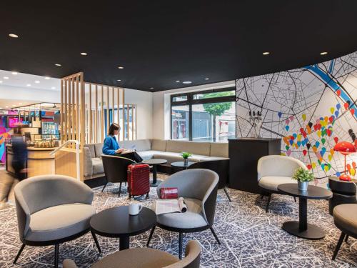 a woman sitting in a waiting room with tables and chairs at ibis Paris Avenue d'Italie 13ème in Paris