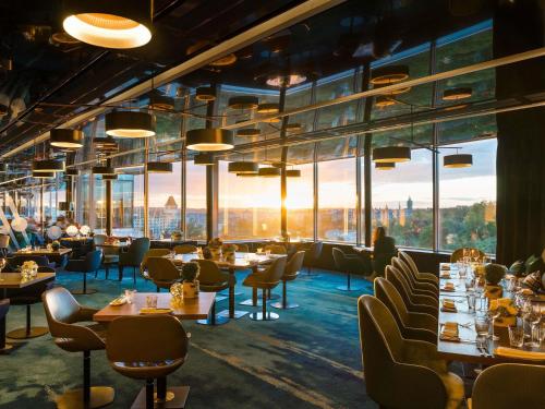 a restaurant with tables and chairs and large windows at Sofitel Luxembourg Le Grand Ducal in Luxembourg