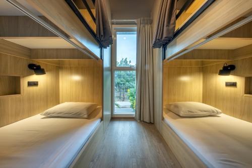 Dos camas en una habitación con ventana. en Ralph Poshtel Pratunam, en Bangkok