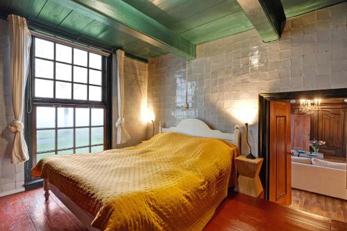 a bedroom with a bed and a window and a tub at De Boerstee in Ruinerwold