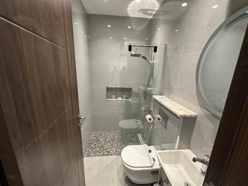 a bathroom with a toilet and a sink and a mirror at Masaken Hotel Apartment in Amman