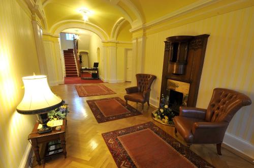 a living room with a fireplace and chairs and a lamp at Woodland House Hotel in Dumfries