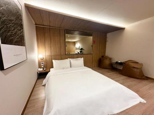 a bedroom with a large white bed and a mirror at Sintra Hotel in Goyang