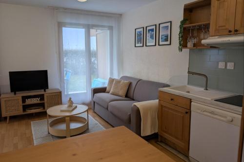 une cuisine et un salon avec un canapé et une table dans l'établissement Cosy du Birdie Logement 4 pers avec piscine, à Giez