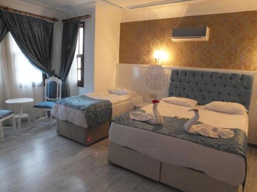une chambre d'hôtel avec 2 lits et 2 cygnes sur les sièges dans l'établissement Urcu Hotel, à Antalya