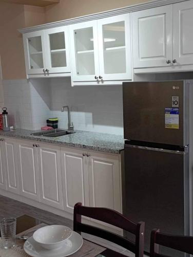 a kitchen with white cabinets and a black refrigerator at Urban Zen - Family Condo with Parking in Nuvali in Calamba